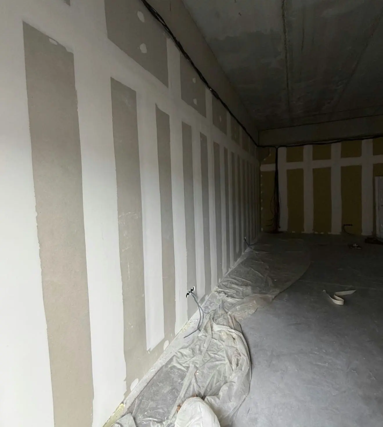 Paramento largo de placa de yeso laminado con el tratamiento de juntas y tornillería aplicado, listo para la fase de acabado