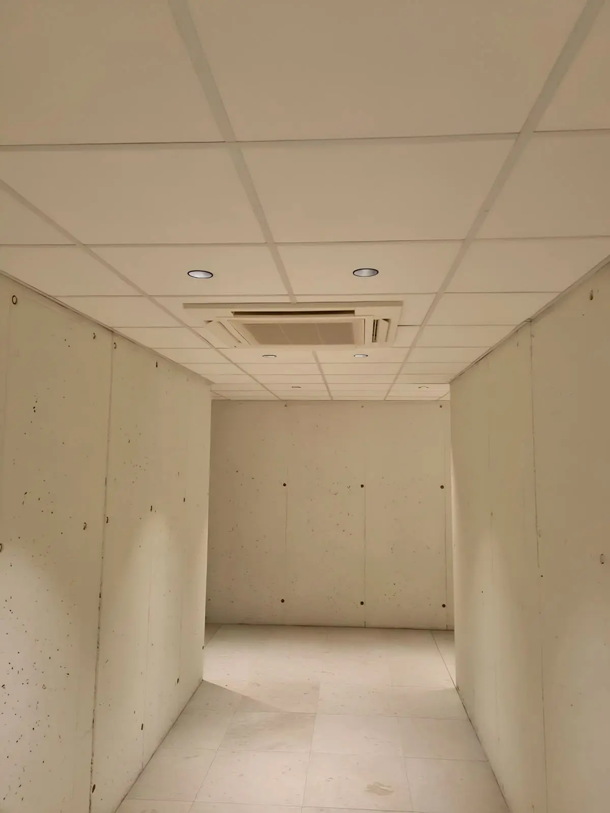 Techo registrable del local cerrado con casete de climatización y downlights integrados, tabiquería PYL a ambos lados